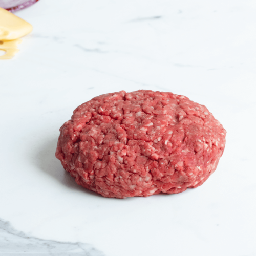 Raw chuck and short rib burger patty on a marble countertop