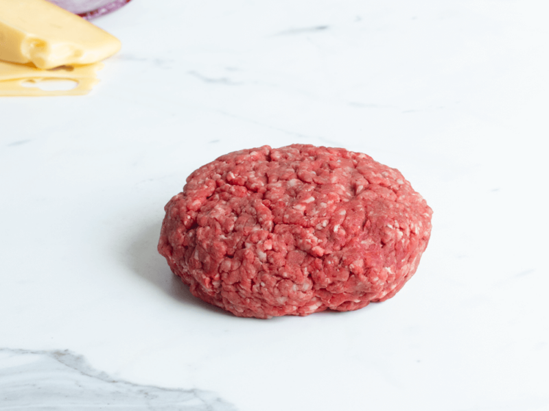 Raw chuck and short rib burger patty on a marble countertop